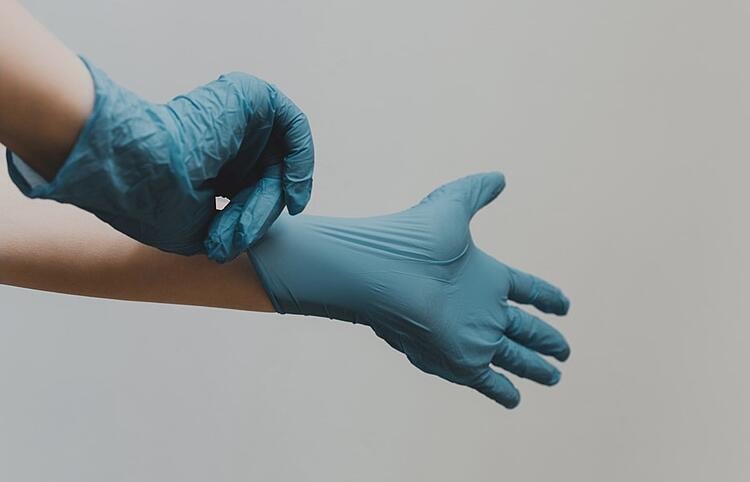 médico colocando luvas azuis para cirurgia