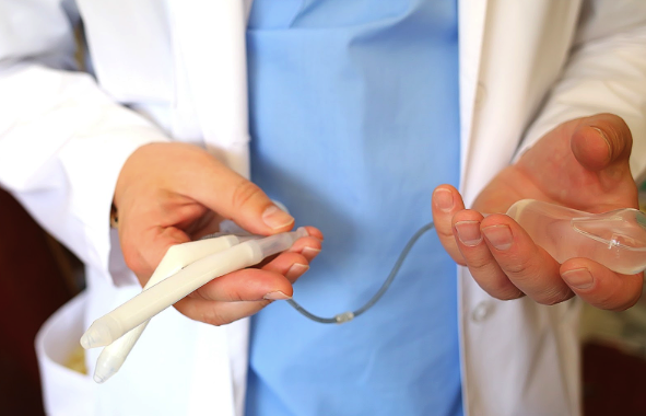 imagem com close de médico segurando uma prótese peniana nas mãoes