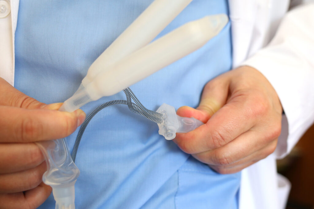 Tipos de prótese peniana inflável: Médico urologista e andrologista segurando uma prótese inflável / hidráulica de 2 volumes
