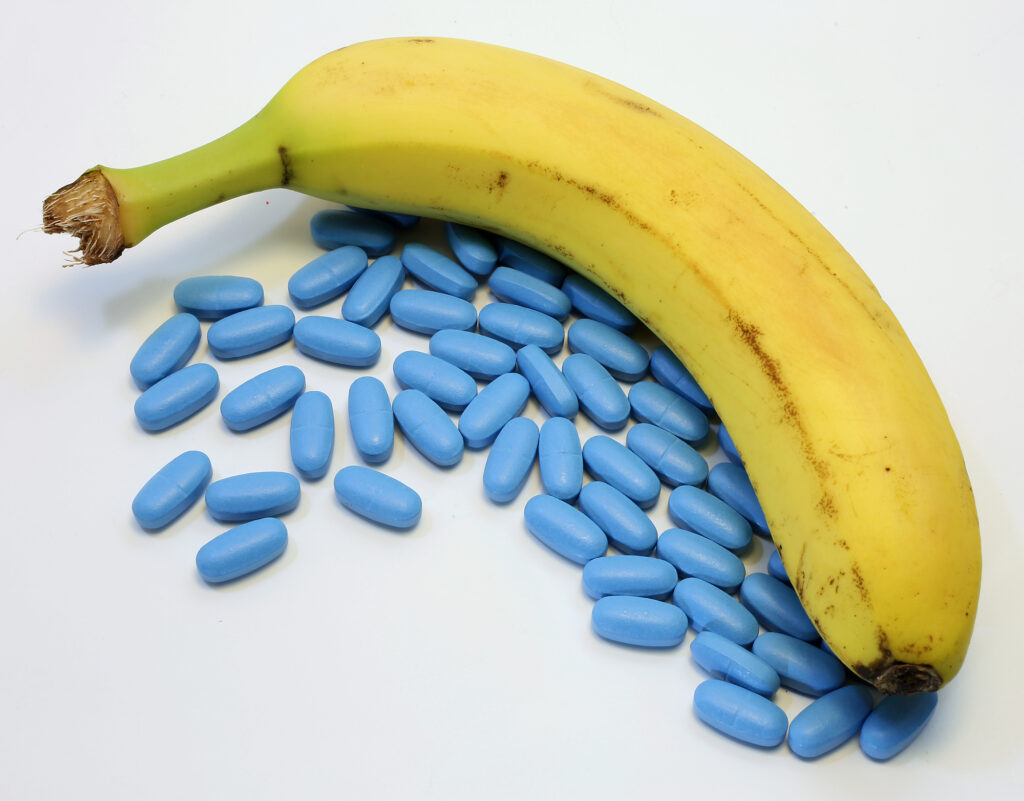 Banana com muitos remédios azuis representando medicamentos para disfunção erétil