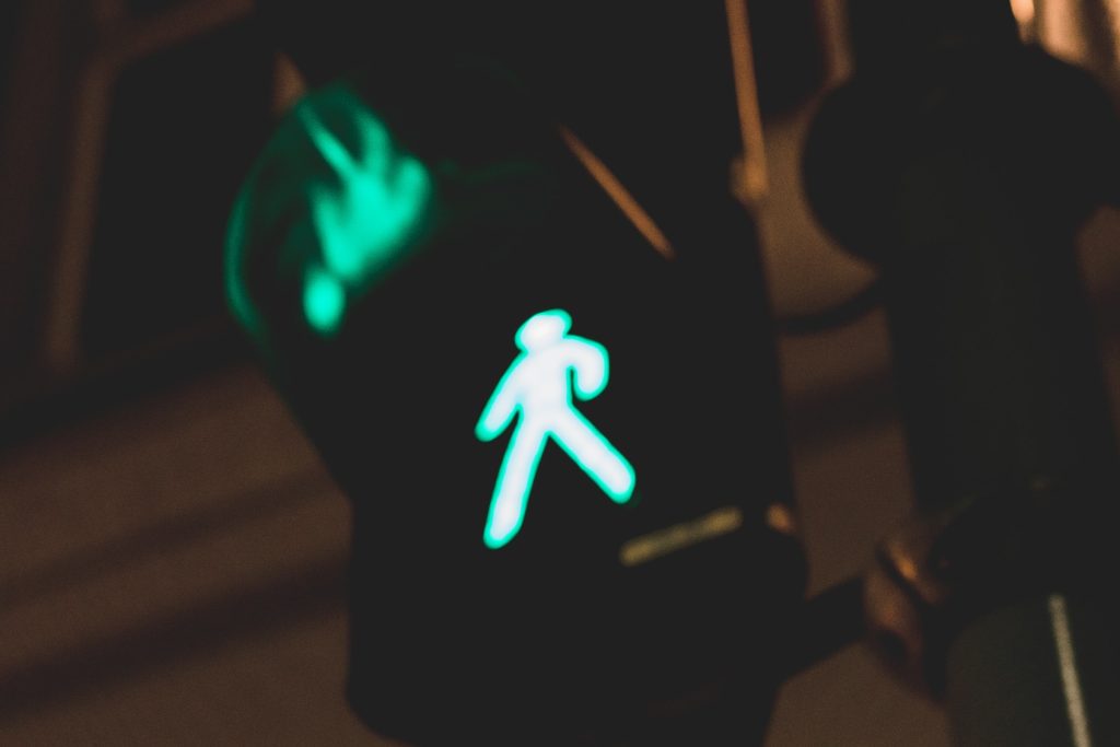 Urban background with a close-up of a traffic light showing a green man symbolizing the 'go' movement and representing the safety and low risk of penile prosthesis rejection