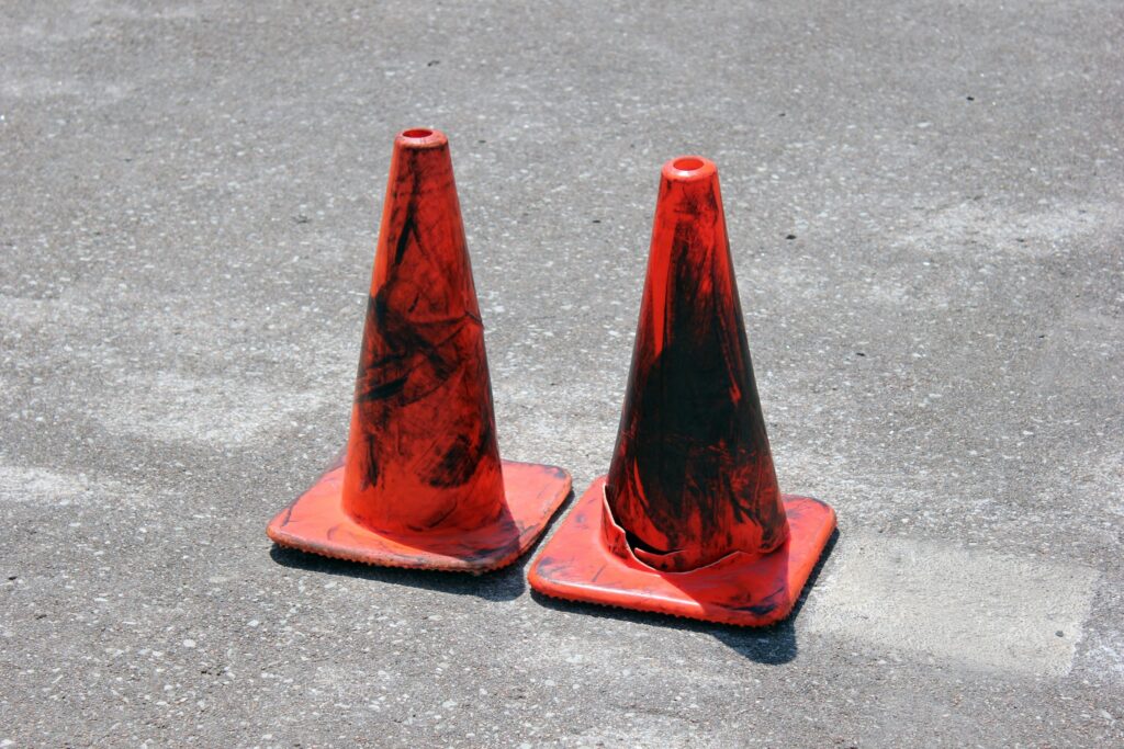 Dois cones de trânsito laranjas sobre asfalto simulando os riscos da bomba peniana a vácuo