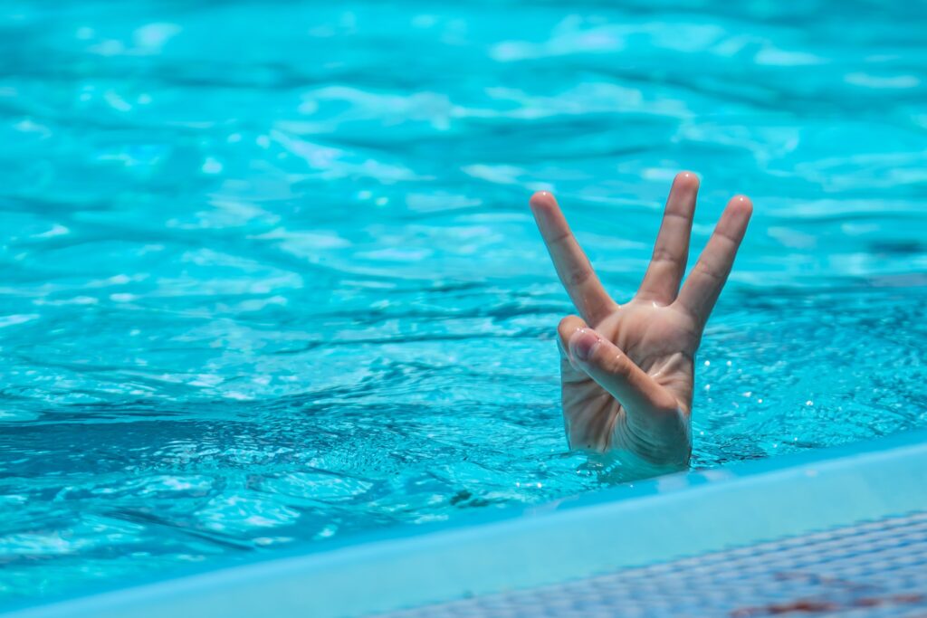 Mão emergendo de uma piscina com três dedos a mostra sinbolizando a prótese peniana inflável de 3 volumes