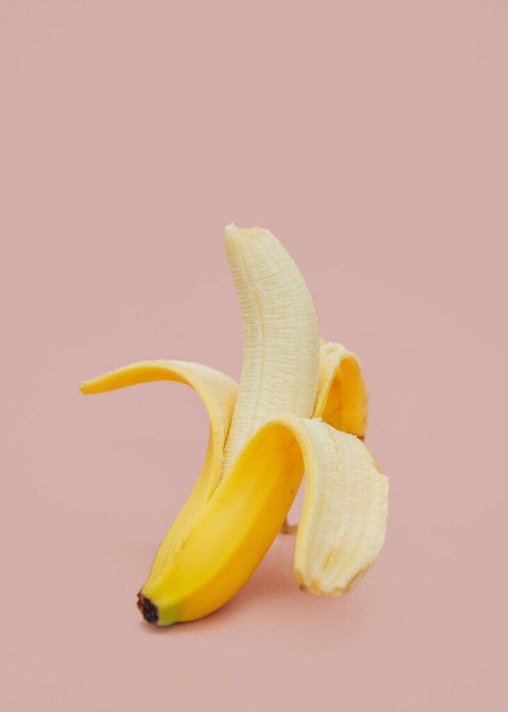 Fundo cor de rosa claro com banana descascada até a metade representando a sensibilidade no pênis