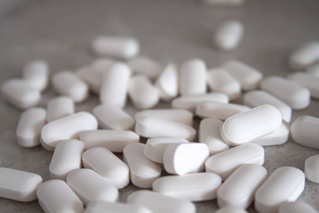Superfície acinzentada com pílulas brancas representando se remédio de pressão alta causa impotência