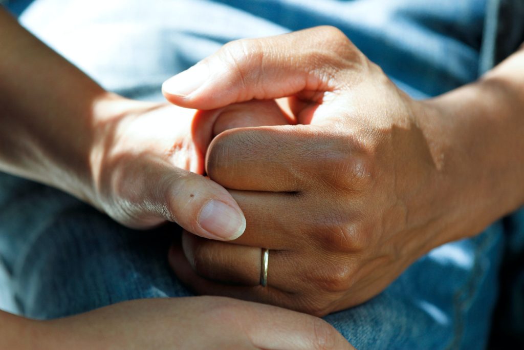 Mão branca masculina com aliança segurando mão feminina branca simbolizando auxília durante tratamento de quimioterapia causa impotência