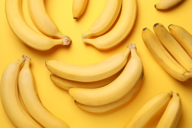 Bananas posicionadas sobre uma superfície amarela, para simular o pênis torto, um sintoma causado pela doença de Peyronie.