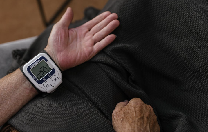 Homem com um equipamento medidor de pressão alta preso no pulso. 