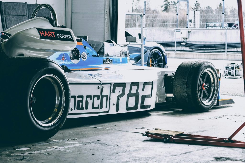 Carro de fórmula 1 preto, azul e branco visto de lateral dentro de uma garagem, com ferramenta ao lado, simbolizando estimulante masculino com efeito imediato