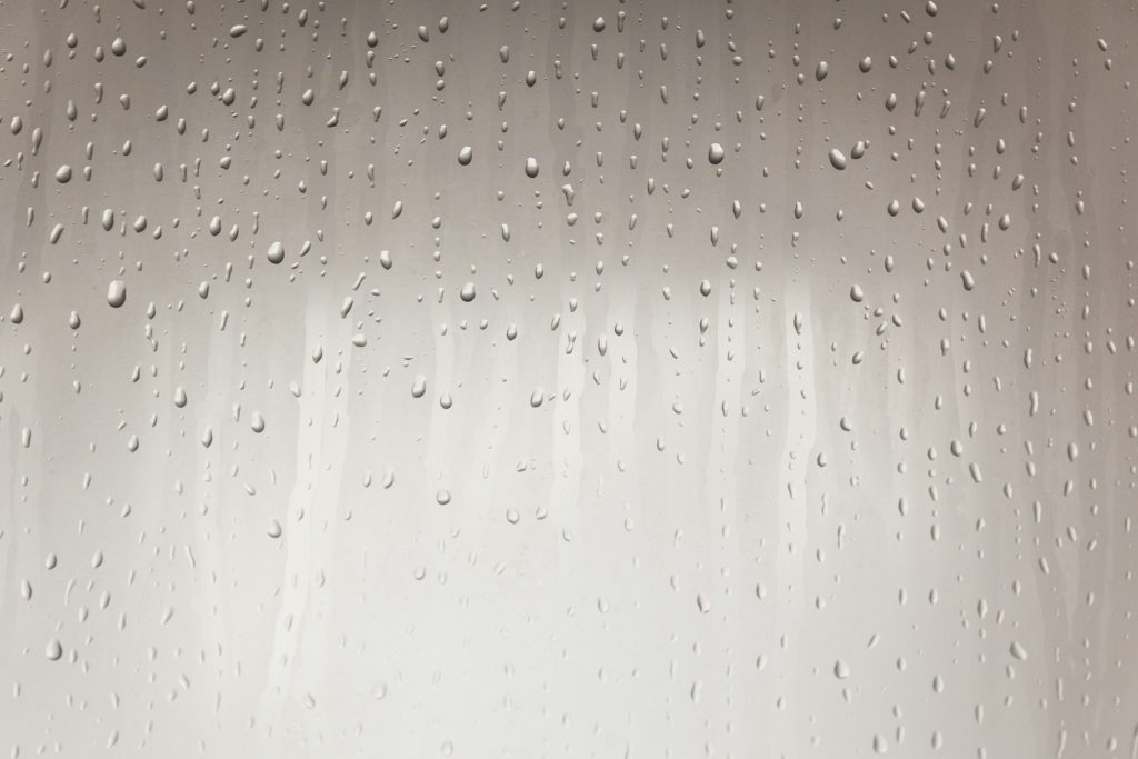 Fogged glass with water droplets and soft finger marks symbolizing how to wash the penis