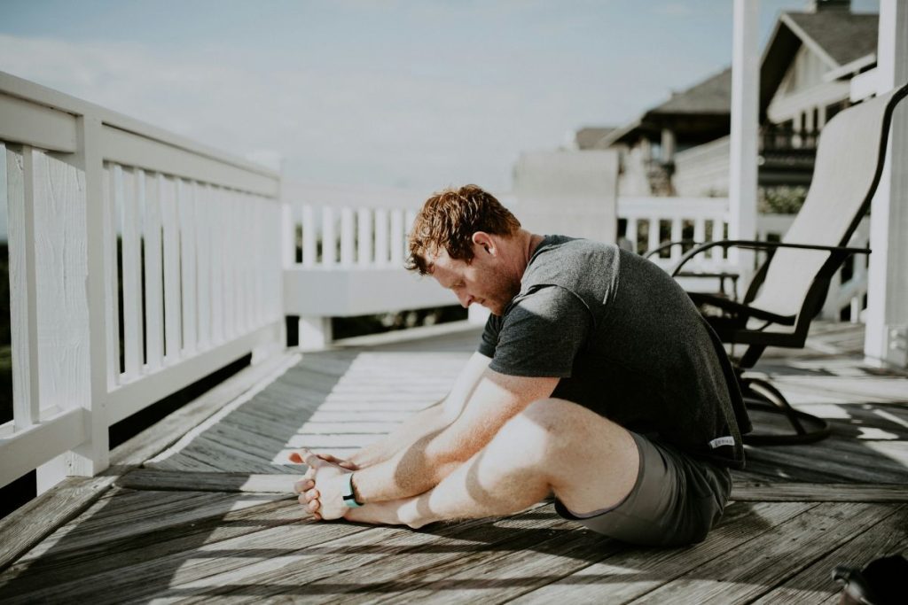 homem sentado na varanda na posição borboleta alongando as pernas para fazer exercícios para assoalho pélvico
