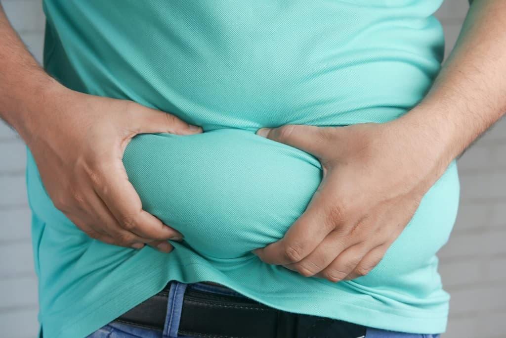 Homem apertando gordura corporal acumulada na barriga