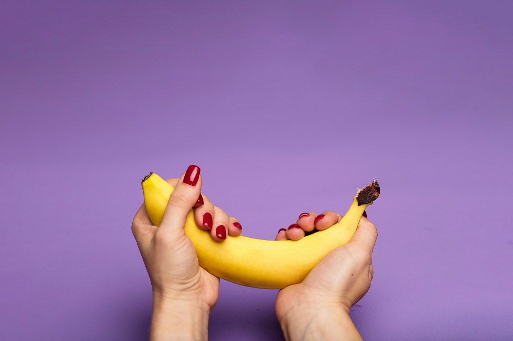 hands holding a banana highlighted against a purple background