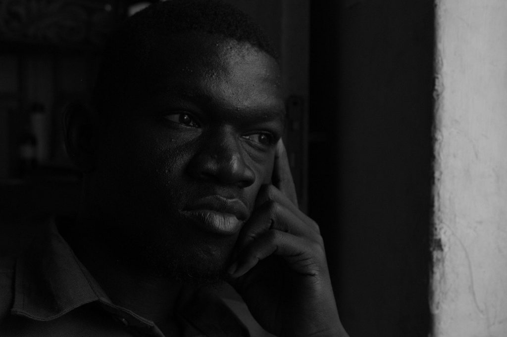 homem negro com ar pensativo com o dedo indicador na lateral do olho e os demais dedos na bochecha.