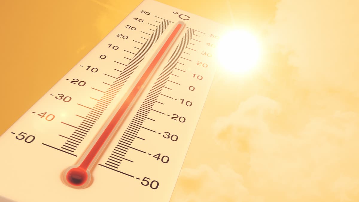 Termômetro de madeira amarelada com números em preto e marcador em vermelho registrando alta temperatura e sol forte acima, representando calor aumenta o tamanho do pênis