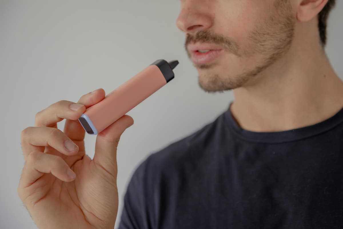 man smoking a pink electronic cigarette