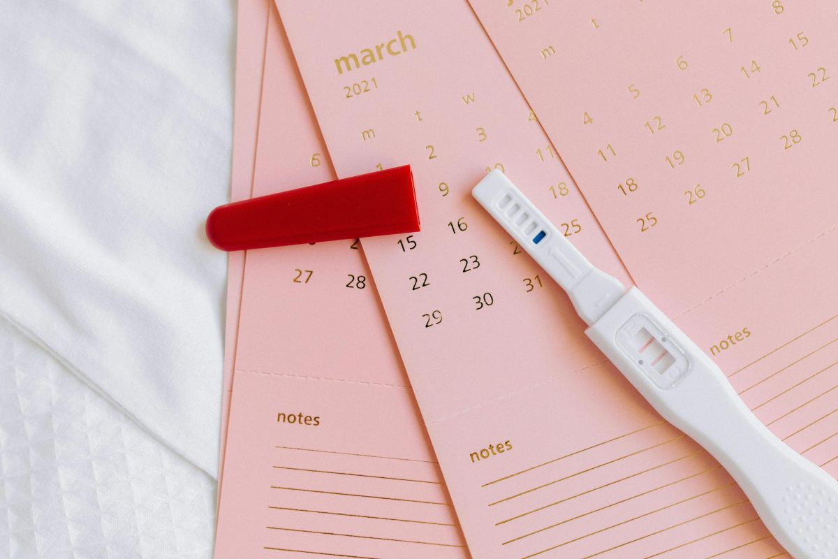 three pink calendar sheets and a white pregnancy test on top of them