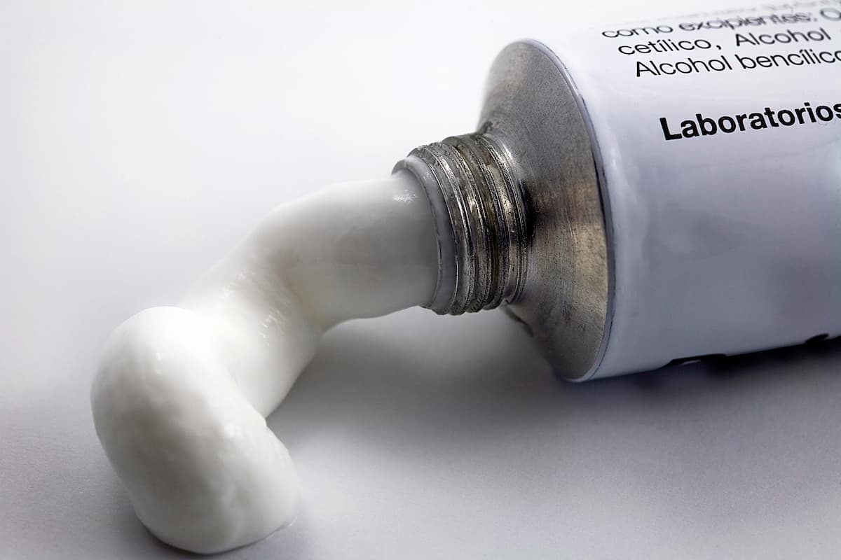 Superfície branca com embalagem de pomada branca de tratmento de micose peniana e conteúdo exposto