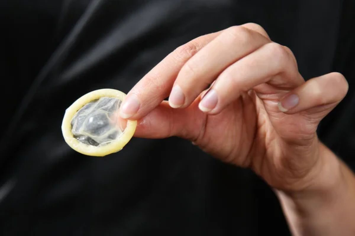 mulher segurando um preservativo