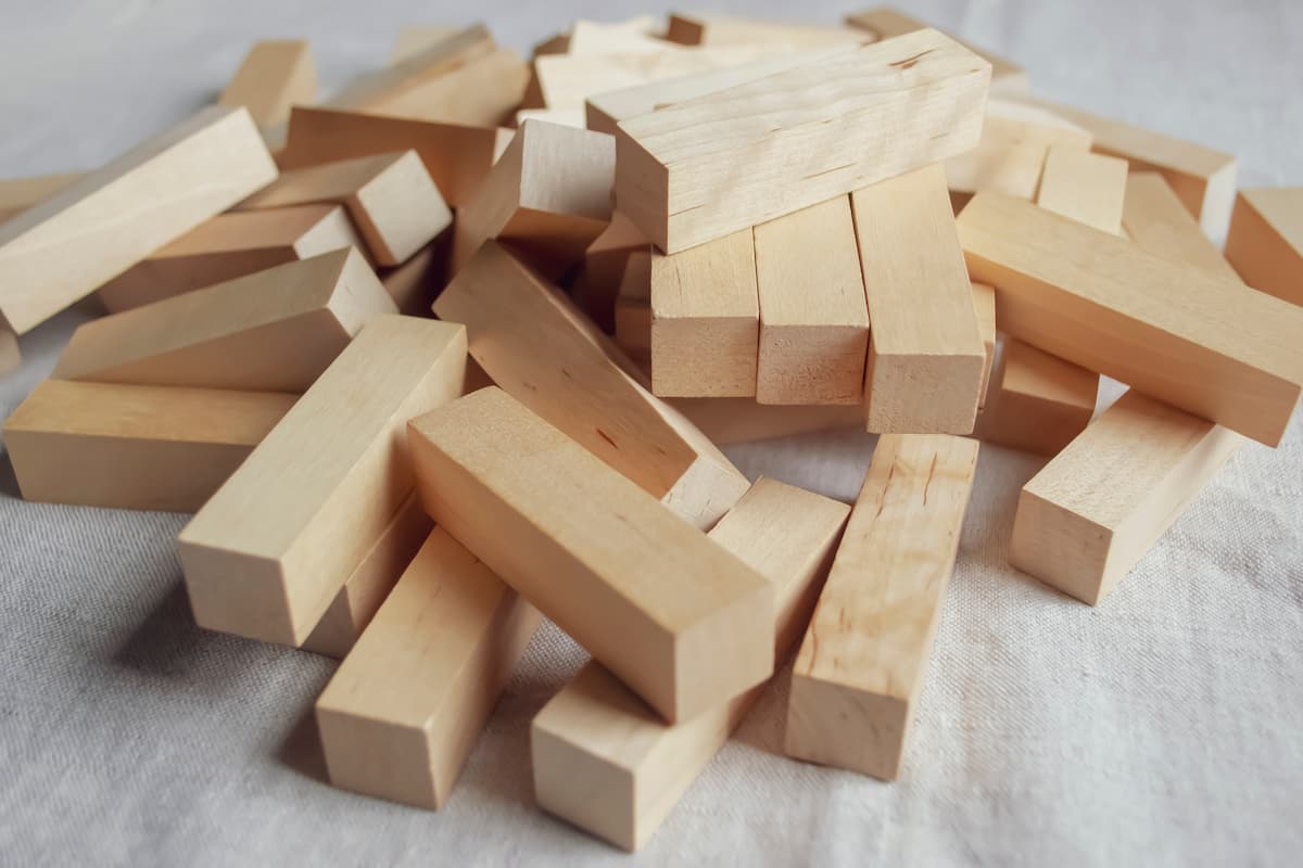 eças de madeira retangulares espalhadas sobre uma superfície clara representando os riscos da cirurgia de prótese peniana