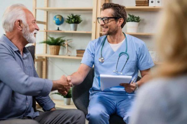 Doctor in an office shaking hands with his patient.