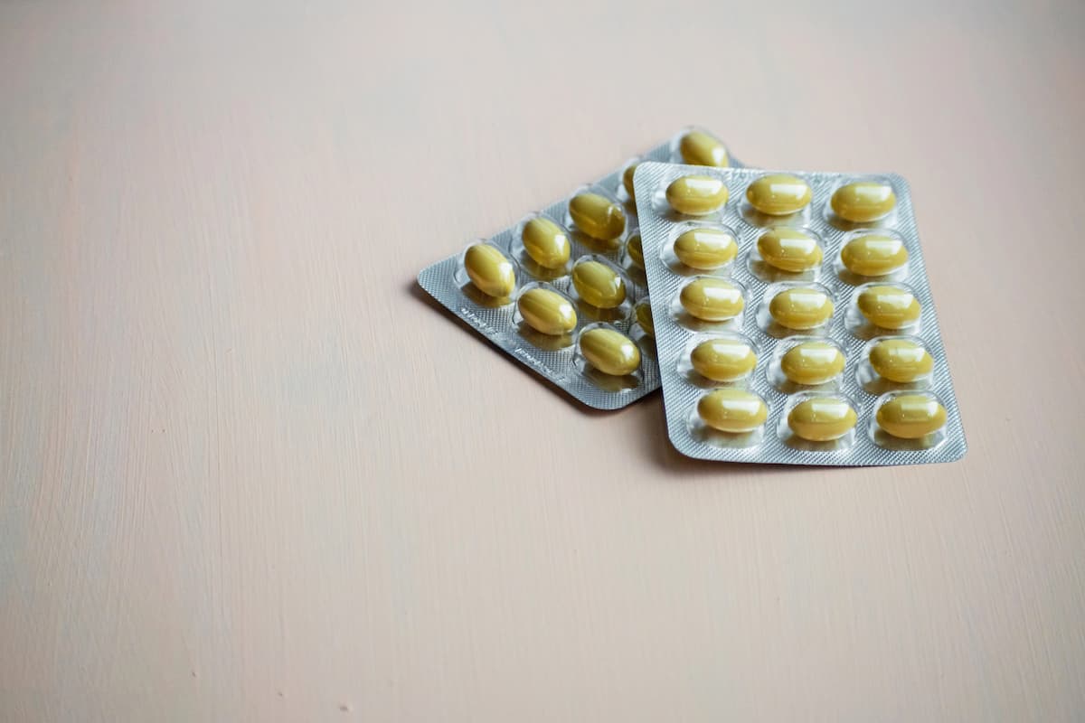 Duas cartelas de comprimidos amarelos sobre superfície de madeira clara representando o uso da tadalafila em jovens