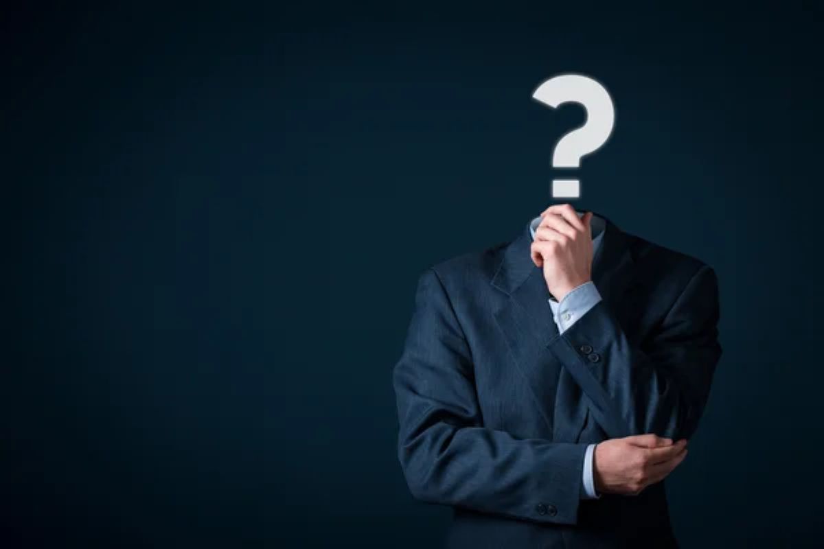 Corpo de homem sem cabeça com um braço dobrado sobre o abdômen e com a mão onde seria o queixo. Onde seria a cabeça tem um ponto de interrogação.