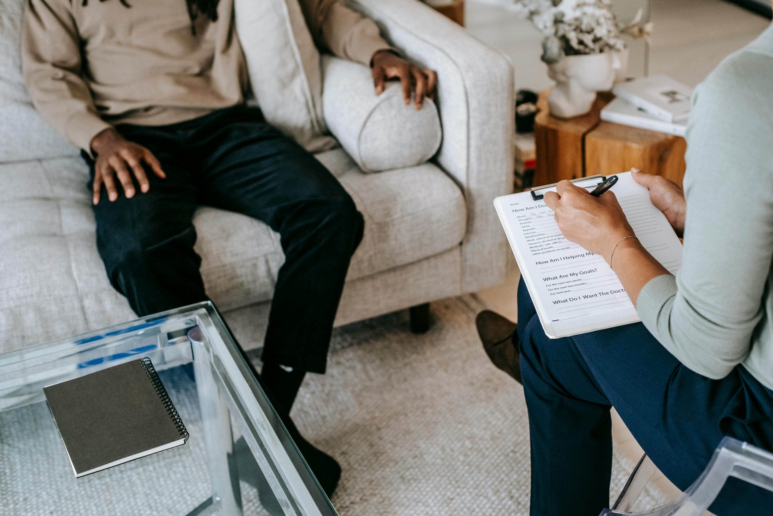 Black man in a counselling session with a therapist making notes.