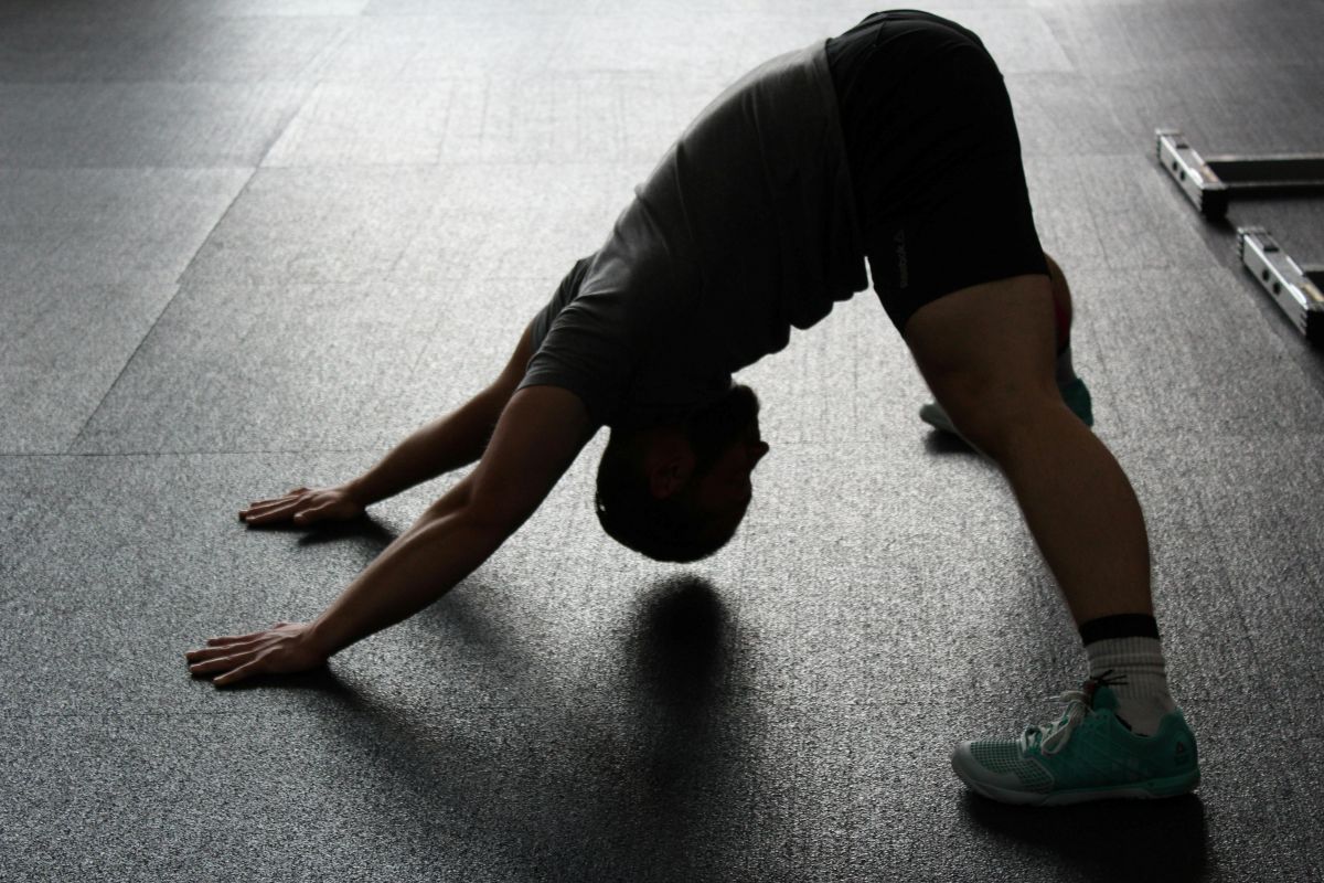 Man stretching in a gym, upward-dog yoga pose.