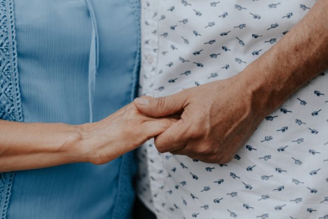 Abdômen de casal idoso branco segurando as mãos representando como apoiar meu marido com disfunção erétil
