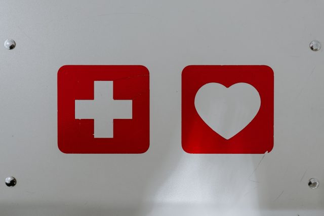 Fundo branco com placar vermelhas com símbolo de cruz e de coração representando a origem das disfunções sexuais