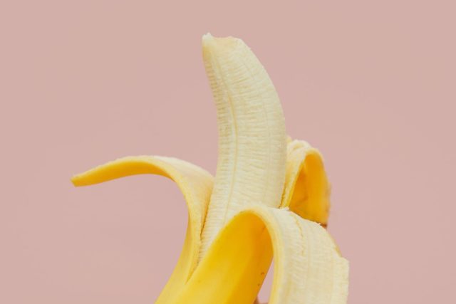 Fundo cor de rosa claro com banana descascada até a metade representando a sensibilidade no pênis